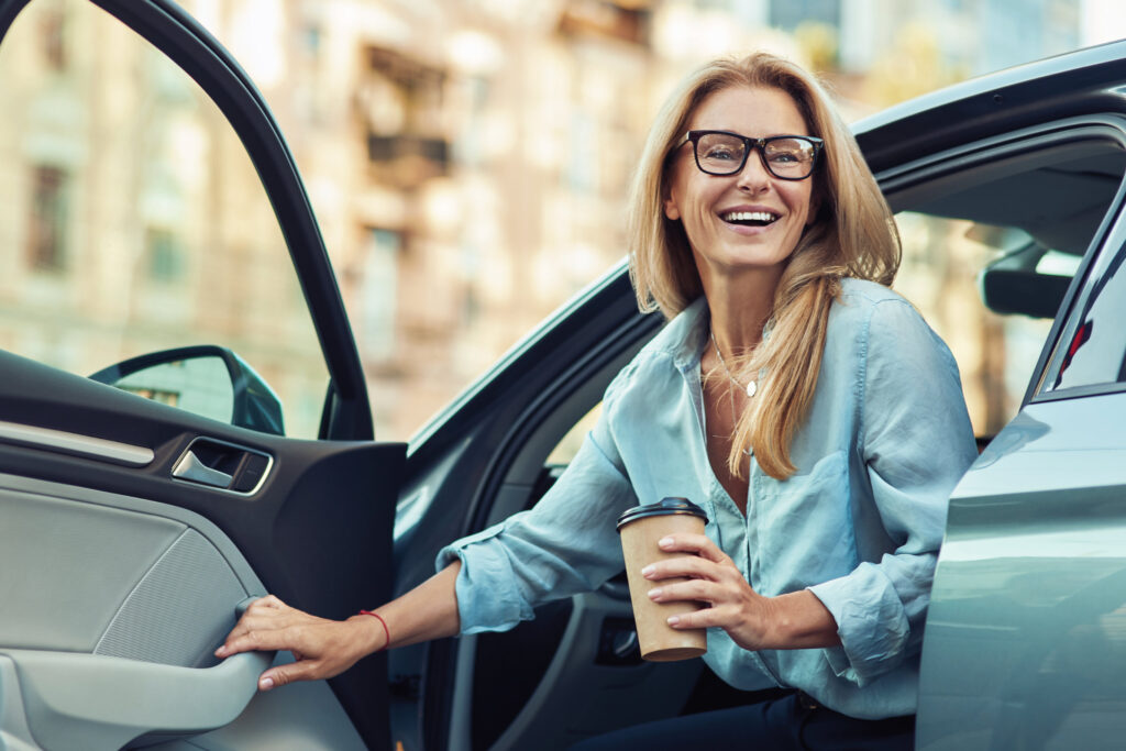 Woman exiting car with a coffee