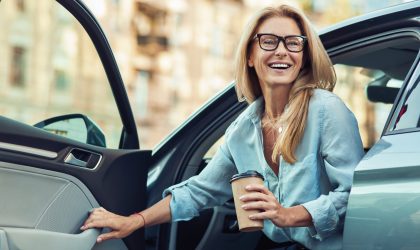 Woman exiting car with a coffee