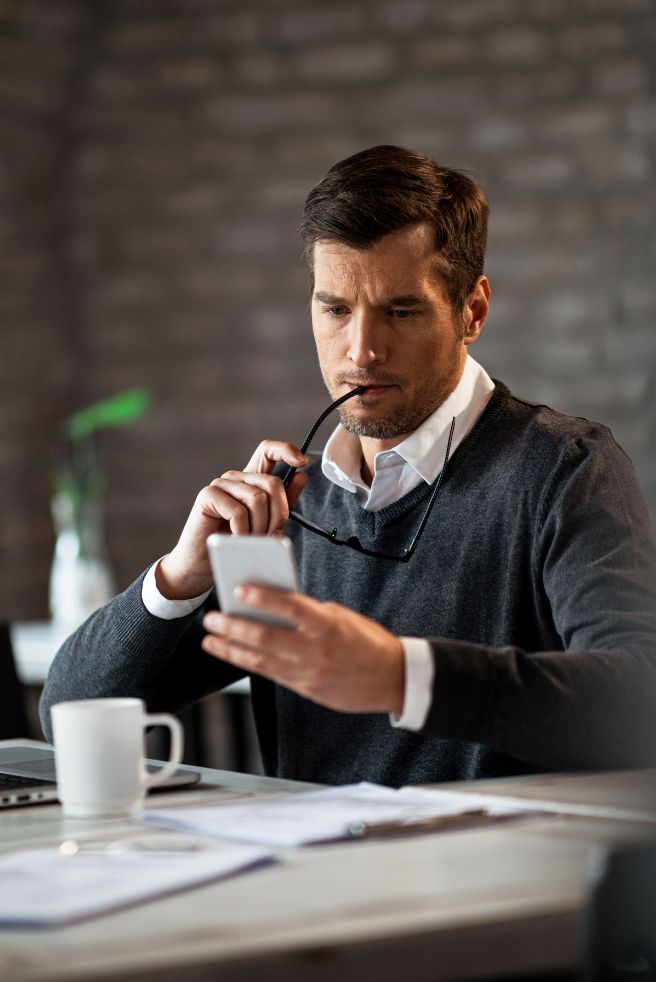Businessman sitting in a coffee shop and looking at data on his mobile phone