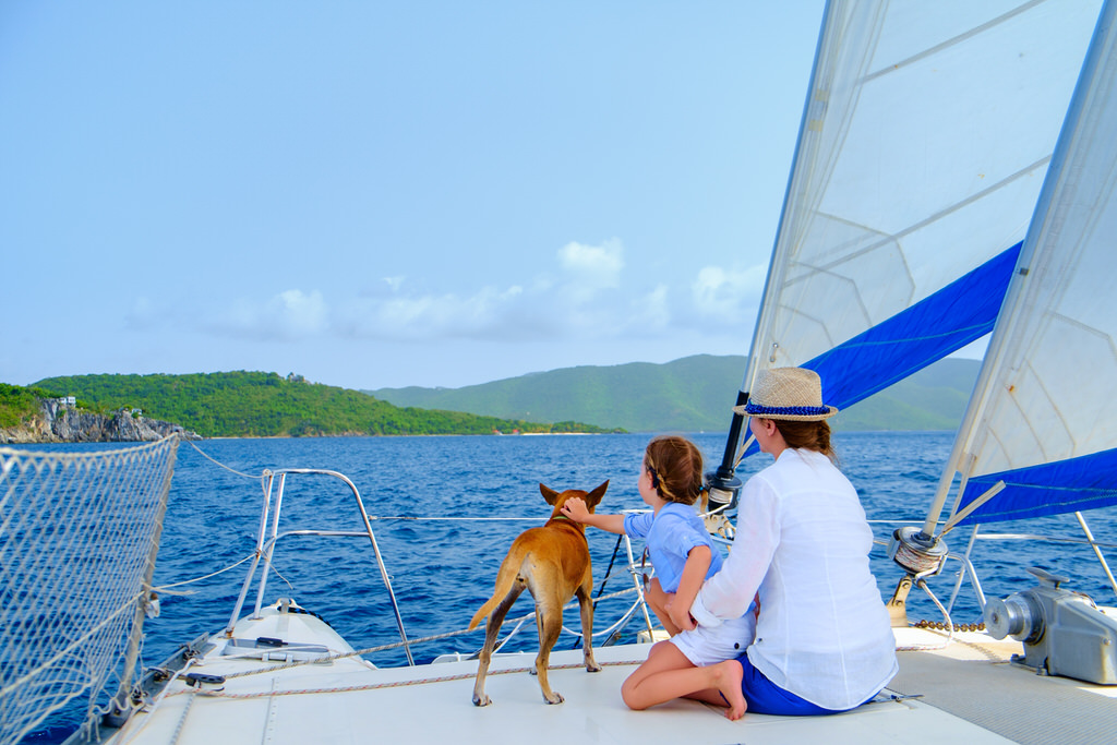 family of mother, child and pet dog sailing on a sunny day