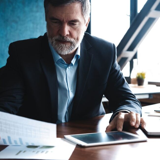 mature male business owner at his desk reading business planning documents