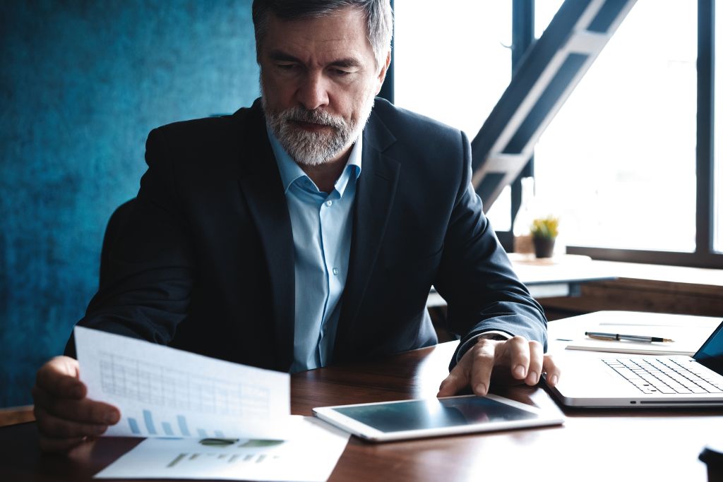 mature male business owner at his desk reading business planning documents