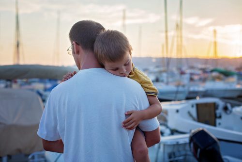 Father, holding his young sleeping child, while enjoying the sun